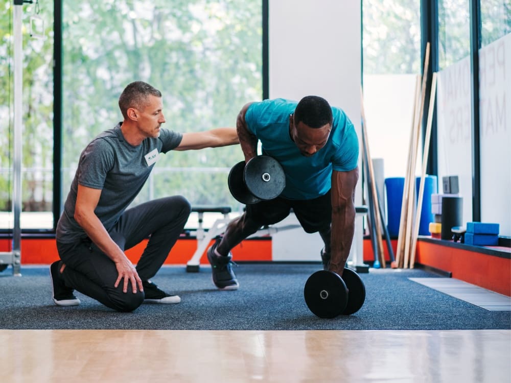 a gym member works with a personal trainer at a gym near me in corpus christi