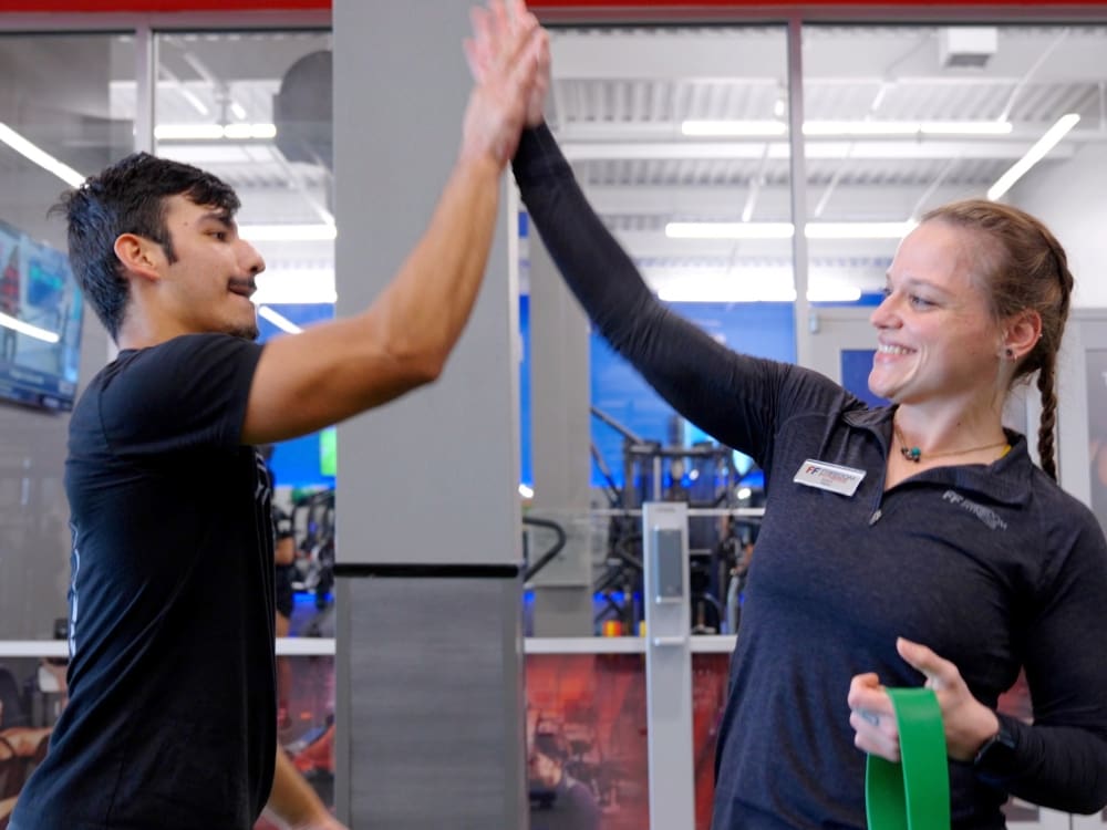 a gym member and personal trainer high five at freedom fitness gym in alameda corpus christi