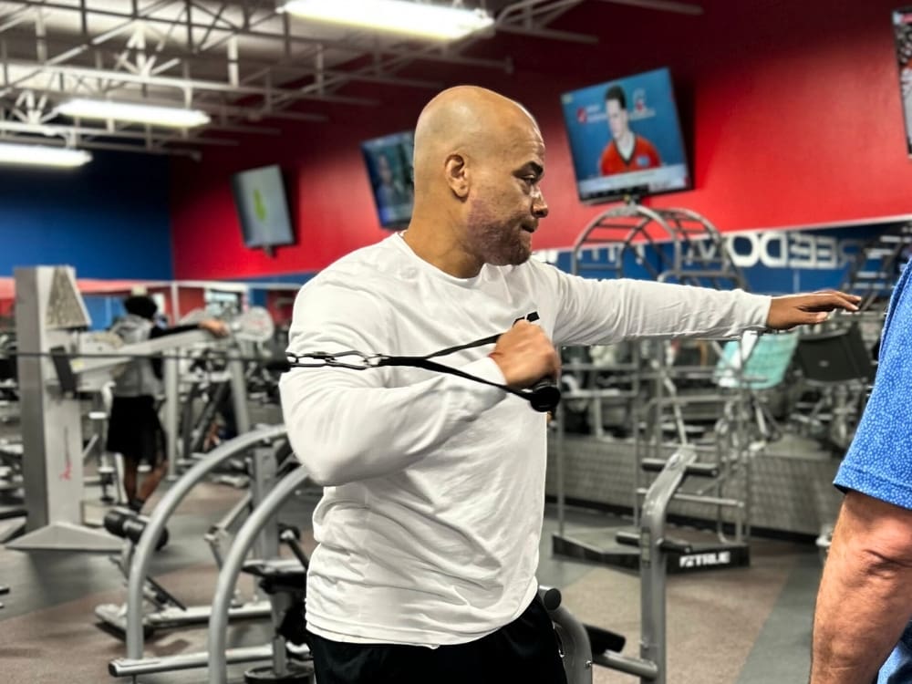 a man uses cable weights for a strength training workout at a gym near me