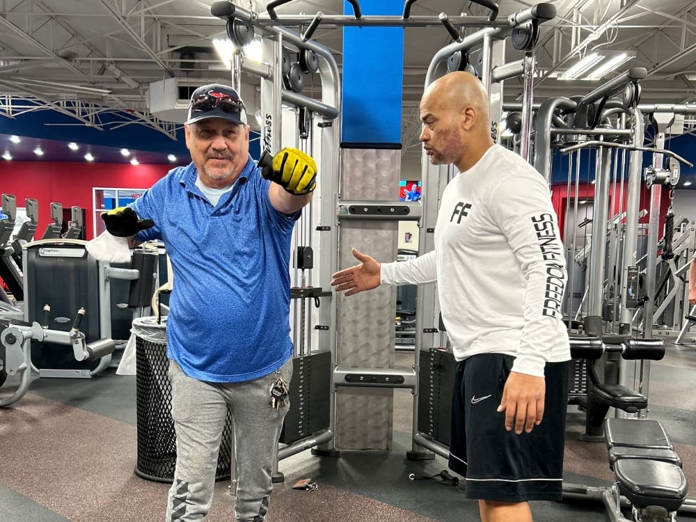 personal trainer helps a man with form on a cable machine at a gym near me