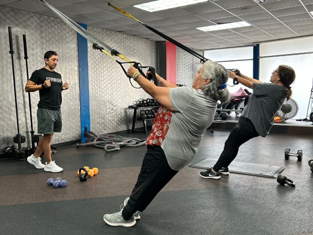 gym members follow instructions from a certified personal trianer during a cable workout at a gym near me