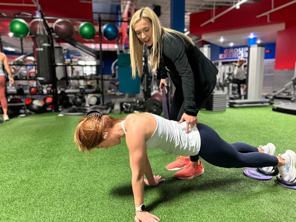 a personal trainer assists a gym member with form during a training session at freedom fitness gym in alameda