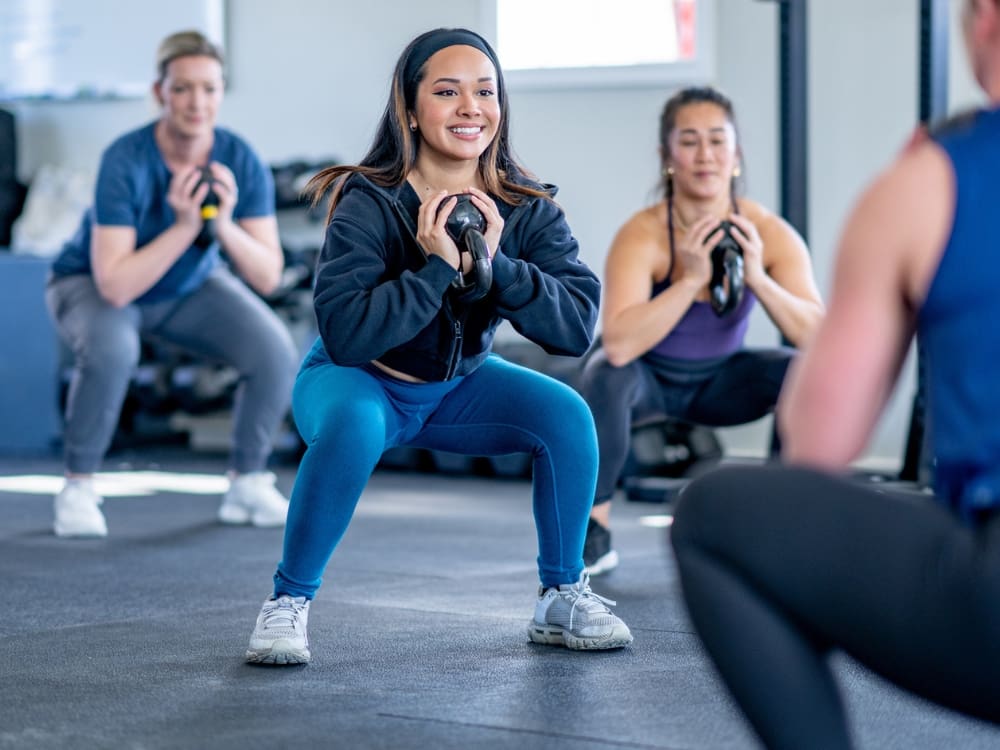 gym members do squats in unison during a small group training bootcamp at a gym near me in alameda corpus christi