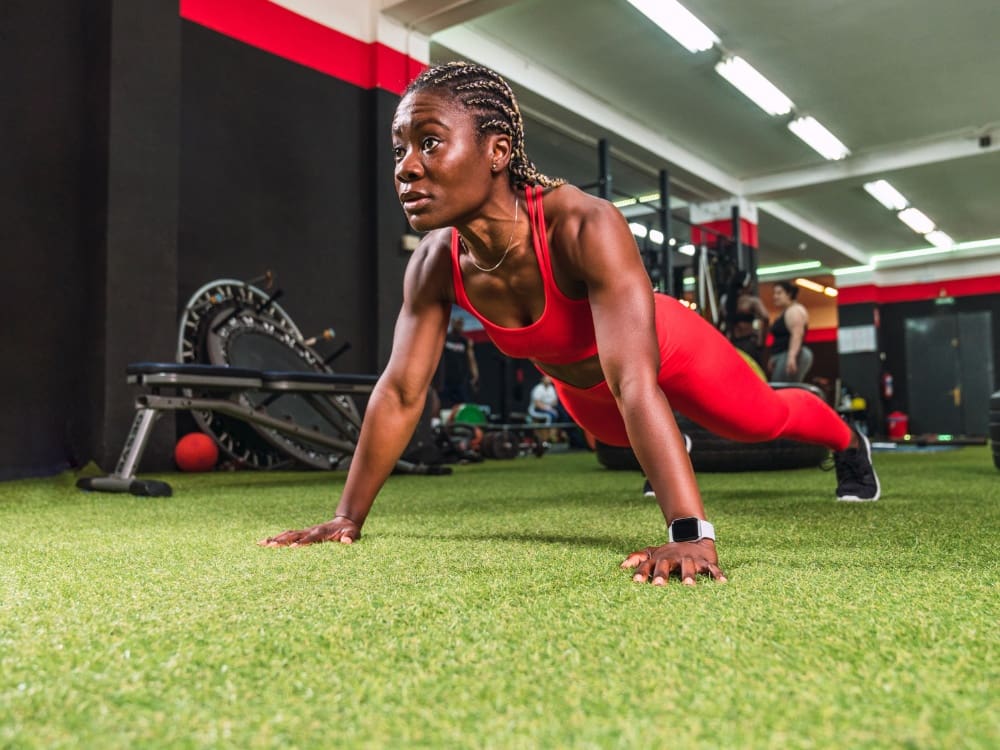 a woman holds a plank in the functional turf training area at a gym near me in calallen