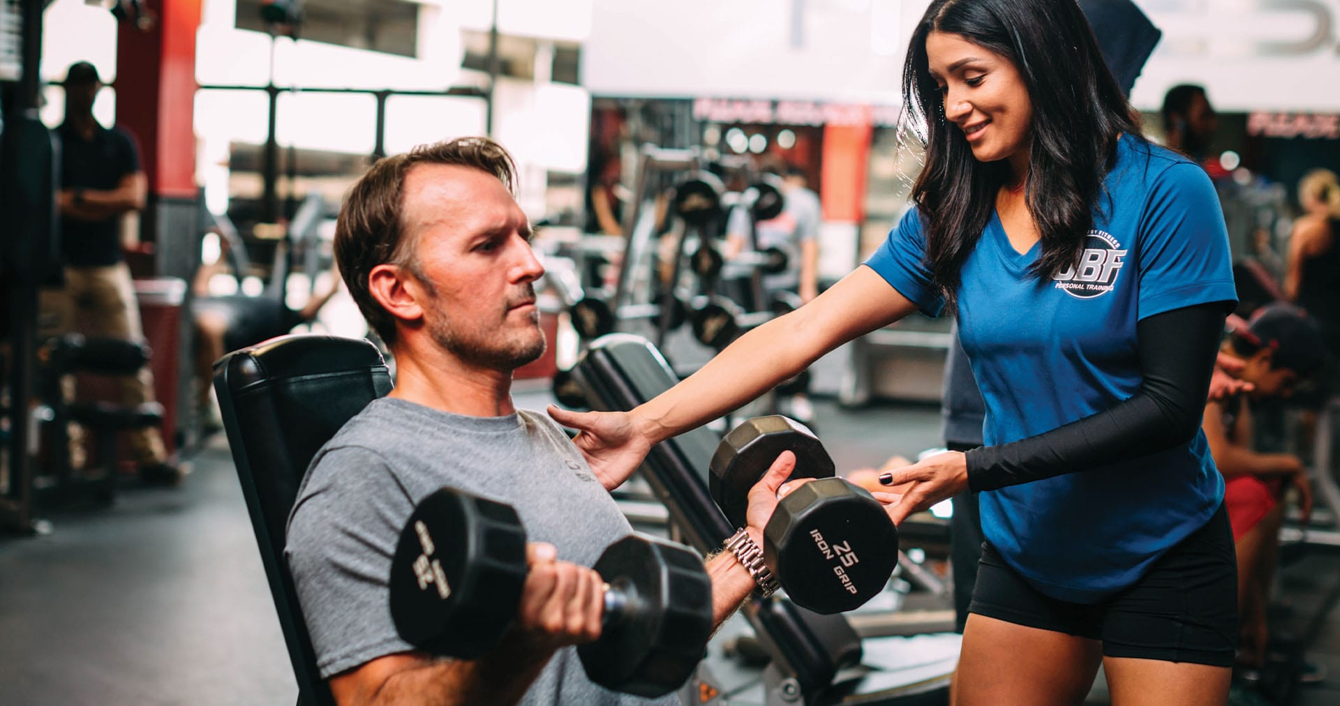 personal trainer teaching a gym member how to do a curl