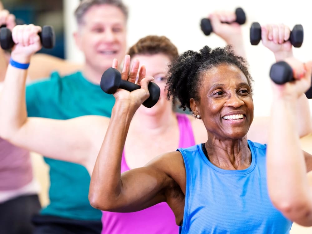 senior gym members lift dumb bells during a group fitness class at freedom fitness gym in saratoga