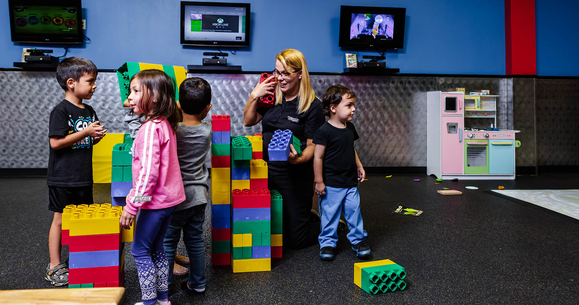 kids with teacher playing with oversized legos at fitness center