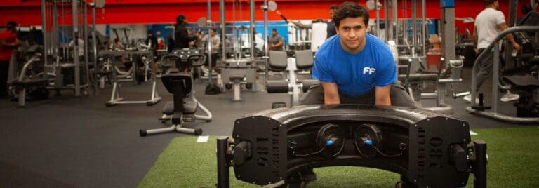 man in a gym working out with a tire on functional turf floor