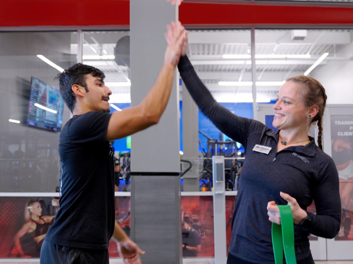 a gym member and personal trainer high five after a personal training session at freedom fitness gym in corpus christi