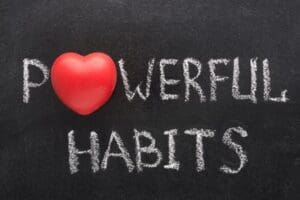 Red heart symbol used as the letter “O” in the word “POWERFUL,” with the phrase “POWERFUL HABITS” written in white chalk on a blackboard background.