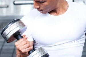 Man performing a dumbbell curl during strength training at a Corpus Christi gym.