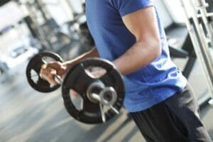 Person performing a barbell curl to build upper-body strength during a workout at our Corpus Christi gyms.